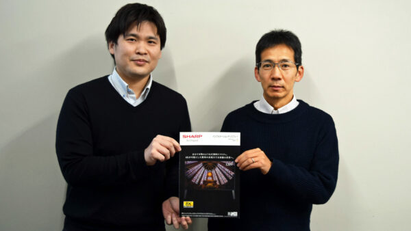 120V型 8K液晶ディスプレイ＜8M-B120C＞のカタログを手にする古田さん（左）と東さん